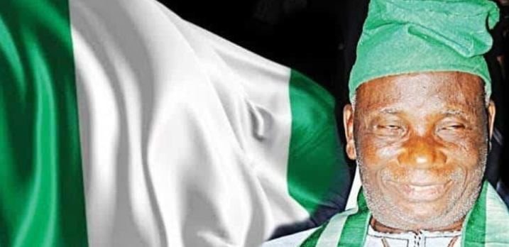 Michael Taiwo Akinkunmi alongside the Nigerian flag